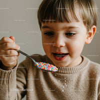 Curious child enjoying colorful sprinkles on spoon
