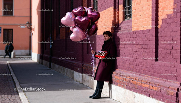 Man Holding Heart Balloons and Chocolates on City Street
