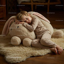 Little boy resting on large plush bunny toy