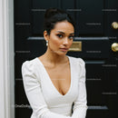 Elegant woman in white dress posing by black door