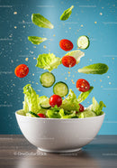 Fresh garden salad ingredients flying into white bowl