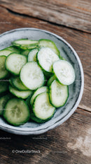 Fresh Sliced Cucumbers in a White Ceramic Bowl on Rustic Wood
