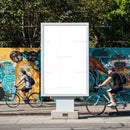 Empty billboard on urban street with cyclists passing by