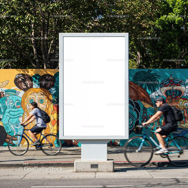 Empty billboard on urban street with cyclists passing by JPG Mockup Image