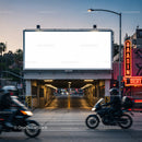 Urban street scene with illuminated blank billboard at dusk