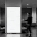 Blurred man walking past bright blank advertising panel