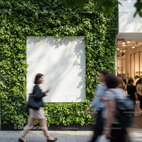 People walking past green wall with blank white billboard