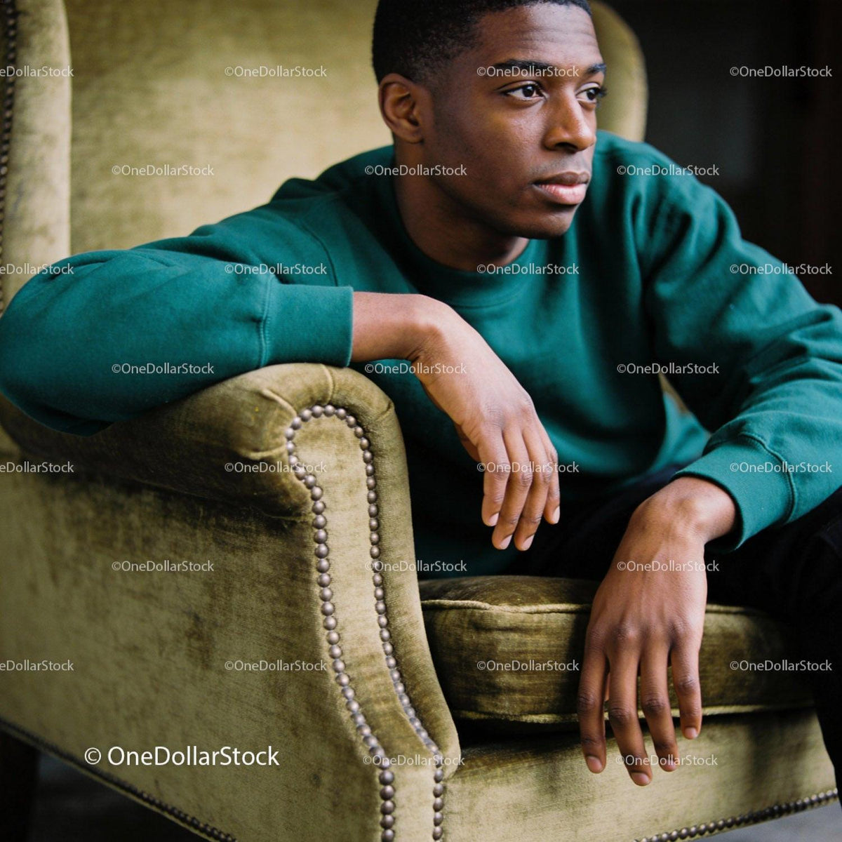 Thoughtful young man sitting on vintage olive armchair