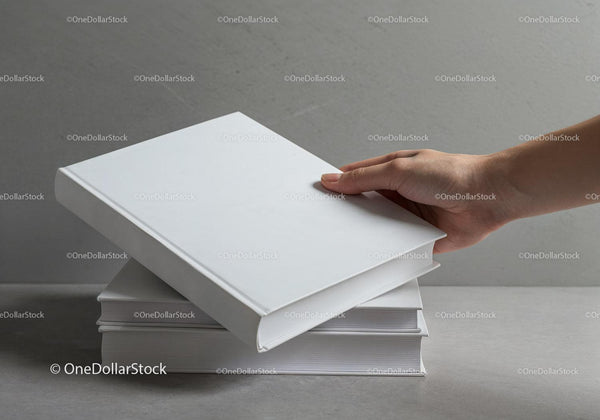 Hand reaching for blank hardcover books on table JPG Mockup Image