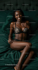 Smiling woman relaxing in elegant lingerie on dark bed