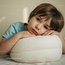 Thoughtful boy resting on soft white cushion