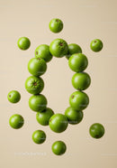 Fresh green limes floating in circular formation on beige
