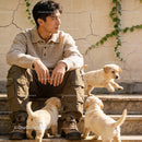 Man Sitting on Steps with Playful Labrador Puppies