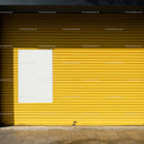 Closed yellow metal shutter with blank white poster