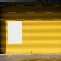 Closed yellow metal shutter with blank white poster