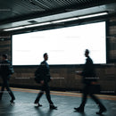 Blurred business commuters walking past blank billboard