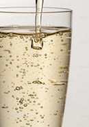 Effervescent golden liquid pouring into glass with bubbles