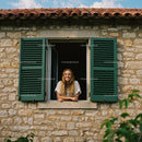 Smiling Woman by a Rustic Window with Green Shutters
