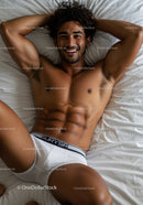 Relaxed young man smiling on bed in white underwear