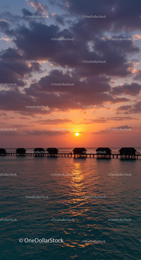 Tropical Sunset Over Ocean with Overwater Bungalows and Dramatic Sky