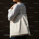 Woman carrying plain canvas tote bag on dark background