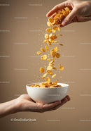 Pouring golden cornflakes into white bowl held by hands
