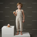 Young boy in beige overalls holding cupcake