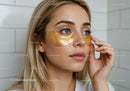 Young Woman Applying Gold Eye Masks for Skin Rejuvenation