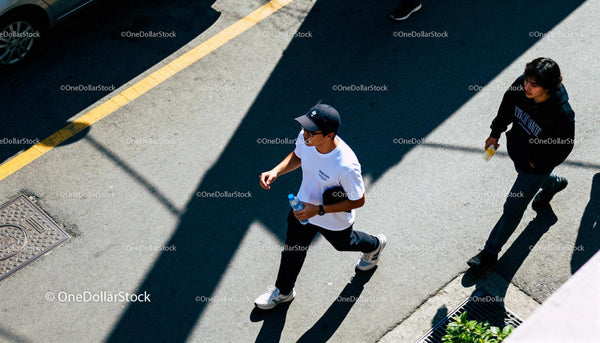 Casual young men walking on sunlit urban street