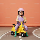 Toddler riding yellow toy scooter with safety helmet