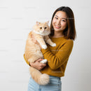 Smiling young woman holding fluffy cream cat