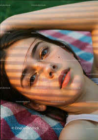 Young woman resting on colorful blanket in warm light