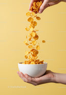 Pouring crispy cornflakes into white bowl held by hand