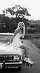Young woman in dress and roller skates on vintage car