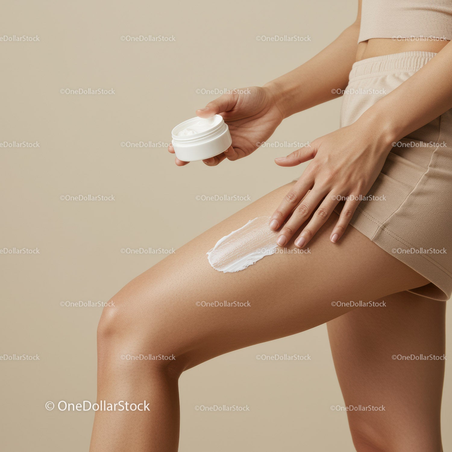 Woman Applying Body Lotion on Thighs Skin in Neutral Setting