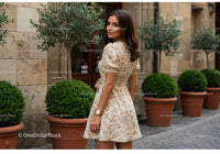 Elegant Woman in Floral Dress Standing Outdoors with Green Plants
