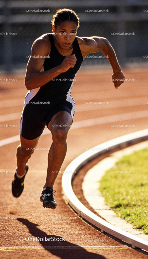 Focused male sprinter accelerating on outdoor track