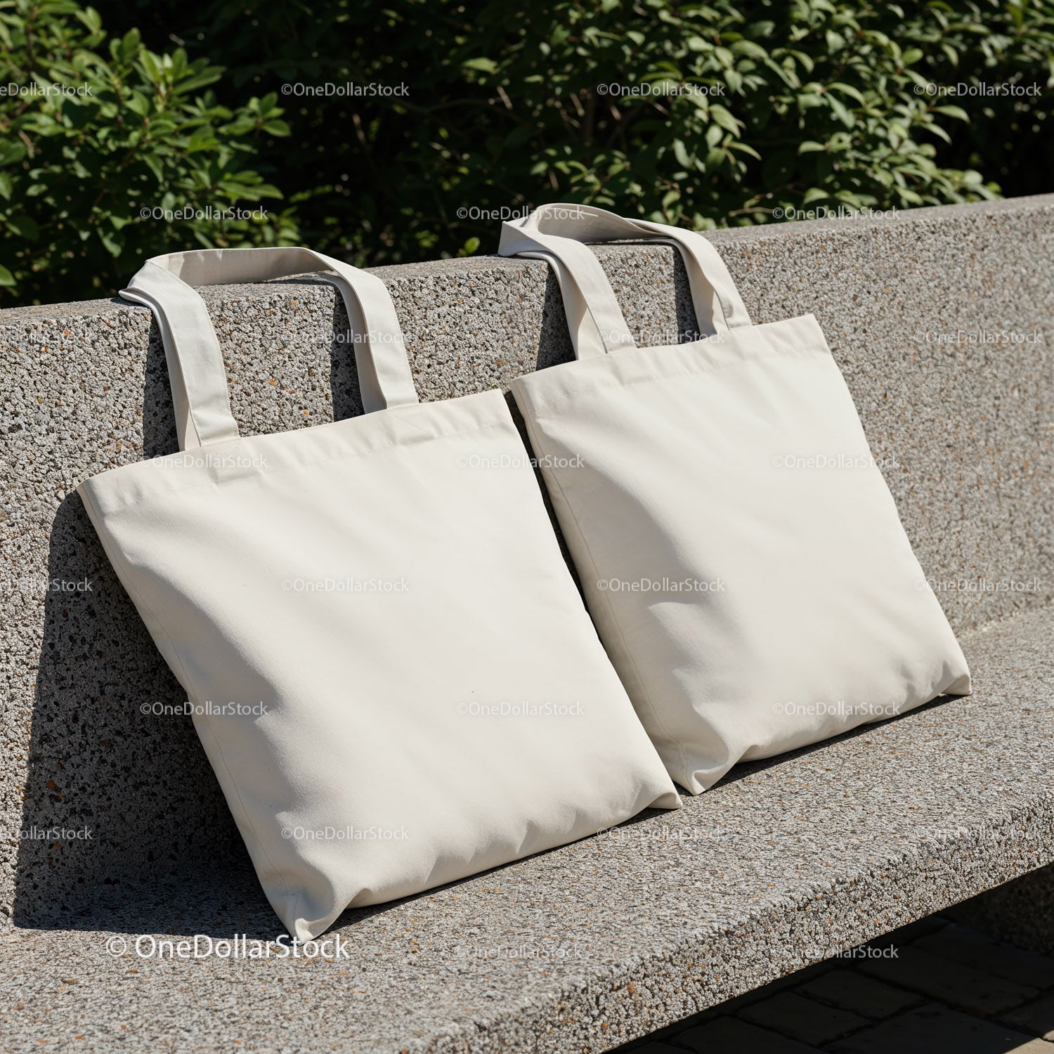 Two Blank Canvas Tote Bags Resting on Stone Bench