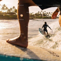 Surfers Riding Waves Near Tropical Shore at Sunset