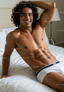 Smiling muscular man relaxing on white bed in underwear