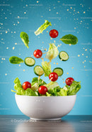 Fresh green salad ingredients falling into bowl