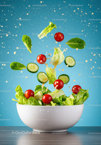 Fresh green salad ingredients falling into bowl