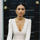 Elegant young woman sitting in front of dark wooden door