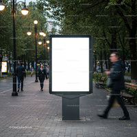 Urban street with illuminated blank billboard at dusk