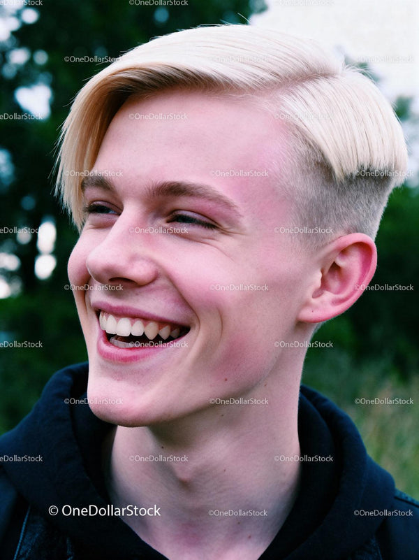 Young man with platinum blonde hair laughing outdoors
