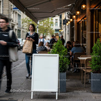 Empty white signboard outside bustling city cafe