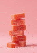 Stack of orange sugar coated gummy candies on pink