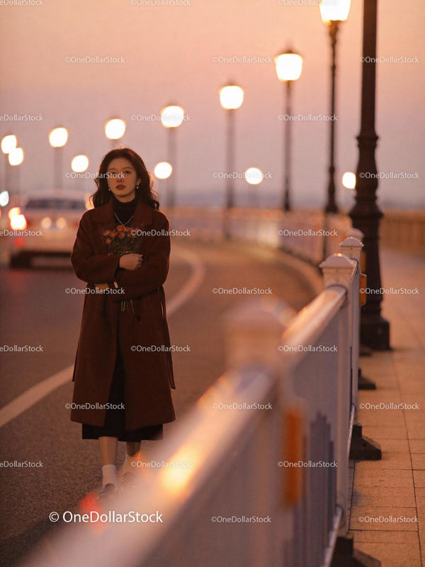 Young woman walking on bridge with roses at sunset