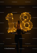 Young woman celebrating 18th birthday with glowing balloons