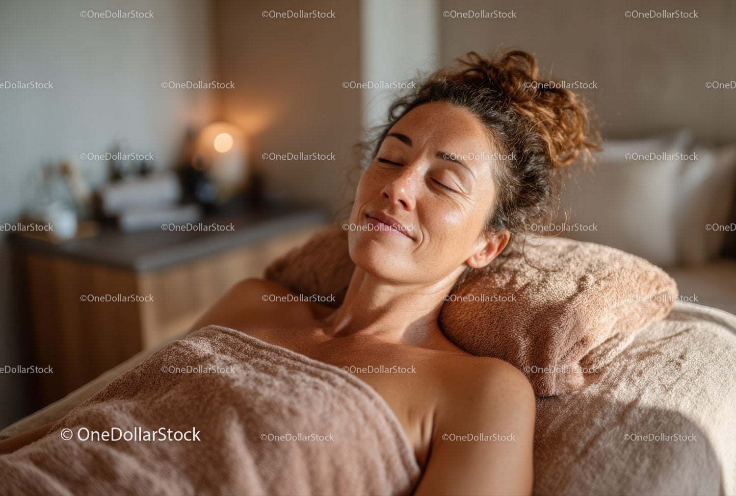 Zrelaksowana kobieta otrzymuje masaż terapeutyczny w przytulnym pokoju spa